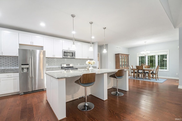 kitchen with stainless steel appliances, white cabinetry, and dark wood finished floors