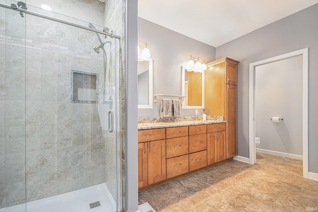 full bathroom featuring toilet, a shower stall, baseboards, and vanity