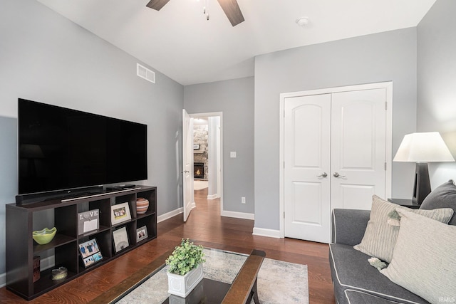 living room featuring dark wood-style floors, baseboards, visible vents, and a ceiling fan