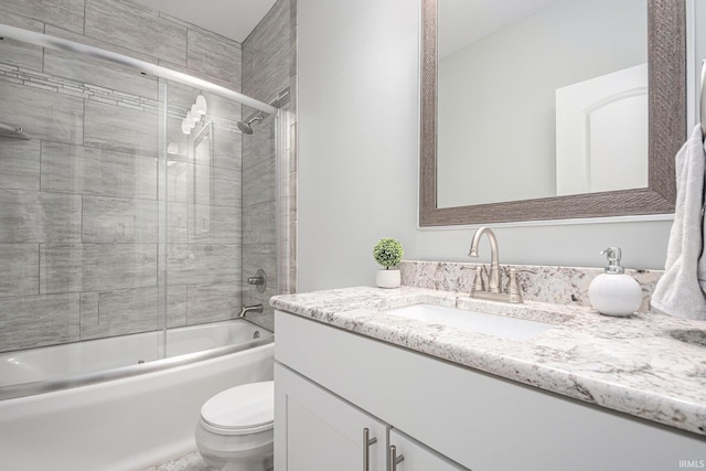 bathroom featuring enclosed tub / shower combo, vanity, and toilet