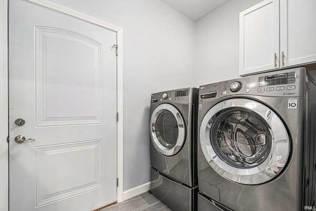 washroom featuring cabinet space, baseboards, and washer and clothes dryer