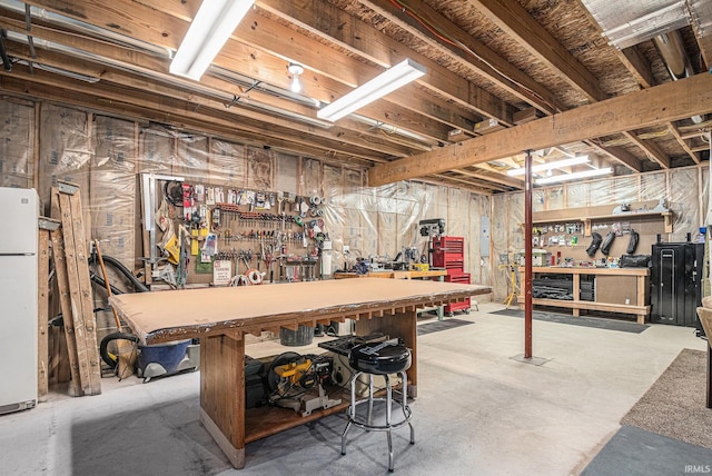 basement featuring freestanding refrigerator and a workshop area