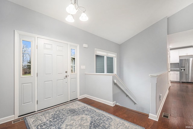 entrance foyer featuring baseboards, visible vents, vaulted ceiling, and dark wood-type flooring