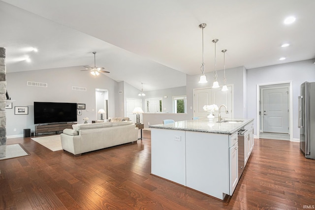 kitchen with visible vents, light stone counters, dark wood-type flooring, stainless steel appliances, and a sink