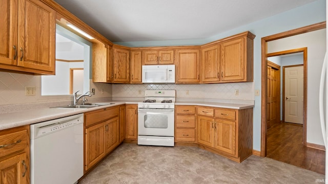 kitchen featuring white appliances, light countertops, a sink, and backsplash