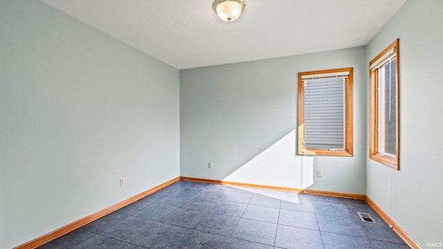 tiled spare room featuring visible vents and baseboards