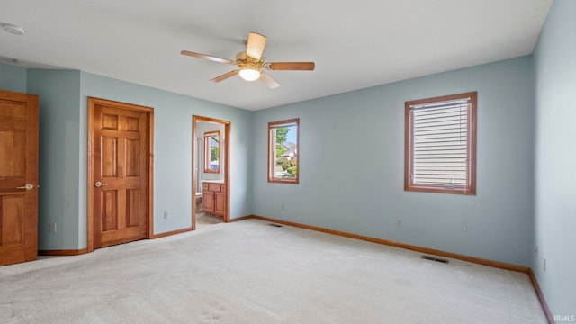 unfurnished bedroom with baseboards, visible vents, connected bathroom, and light colored carpet