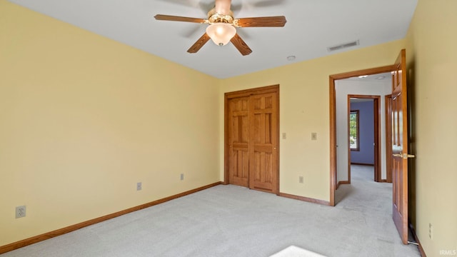 unfurnished bedroom with a closet, light colored carpet, visible vents, ceiling fan, and baseboards