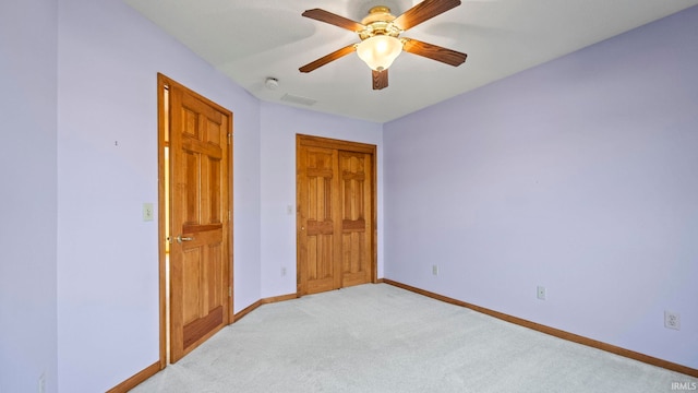 unfurnished bedroom featuring light colored carpet, a ceiling fan, visible vents, baseboards, and a closet