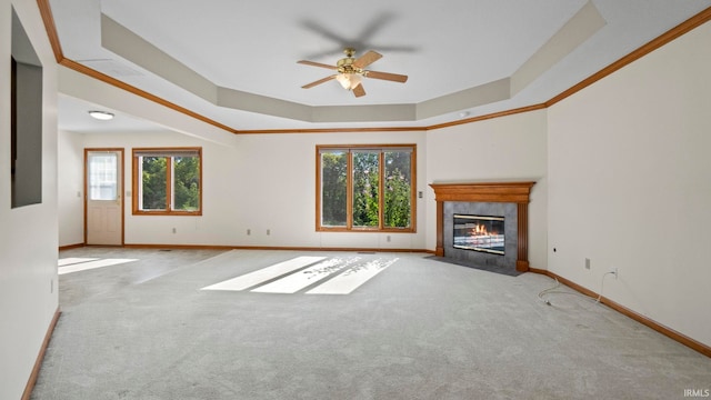 unfurnished living room featuring a tile fireplace, carpet floors, baseboards, ornamental molding, and a tray ceiling