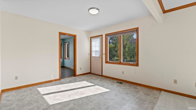 empty room featuring beamed ceiling, visible vents, and baseboards