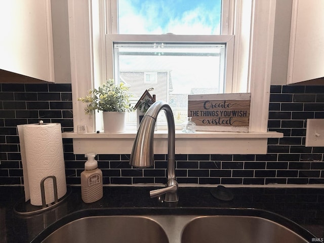 details featuring backsplash, dark countertops, a sink, and white cabinets