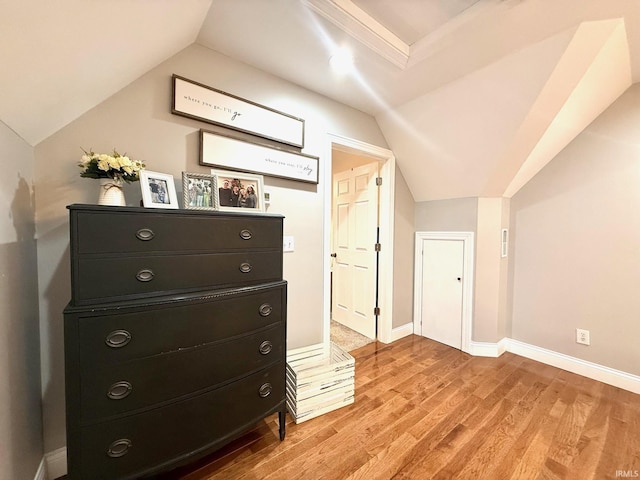 interior space featuring lofted ceiling, light wood finished floors, and baseboards