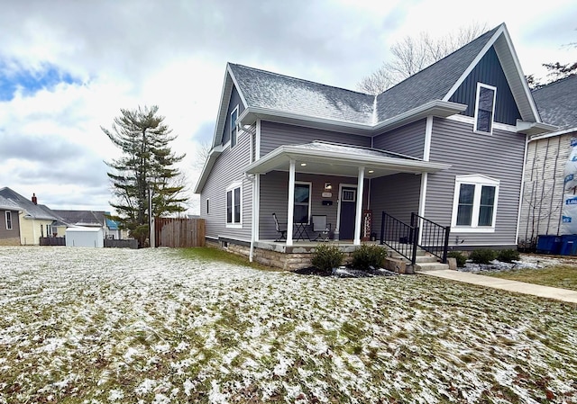 traditional-style home featuring covered porch, fence, and roof with shingles