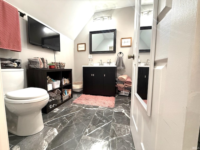 bathroom with lofted ceiling, marble finish floor, vanity, and toilet