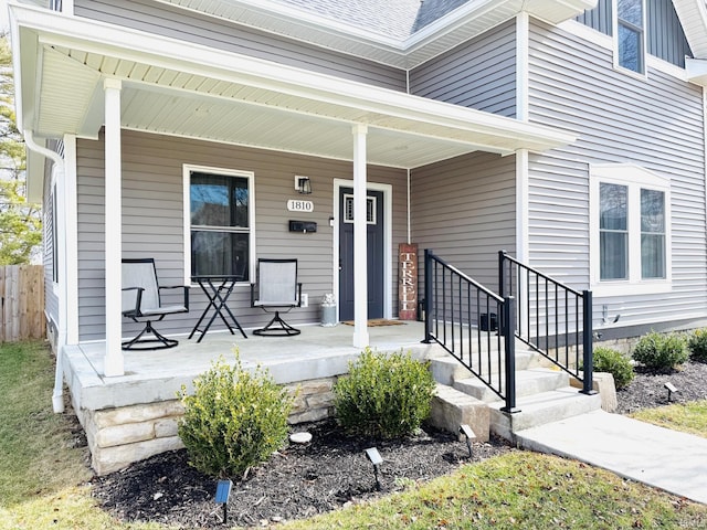 property entrance with covered porch and a shingled roof