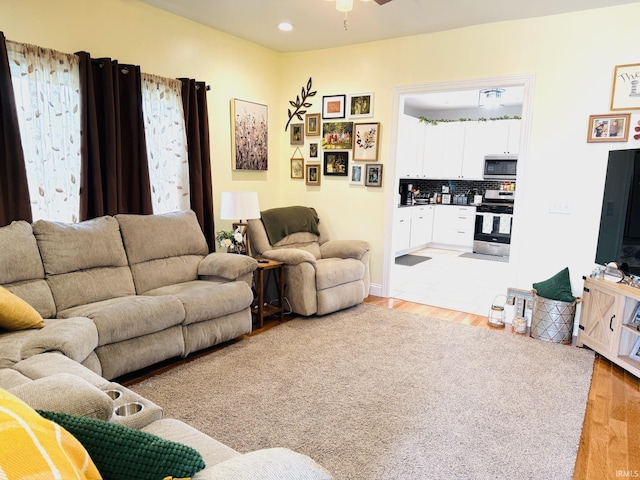 living room with light wood-type flooring, ceiling fan, and recessed lighting