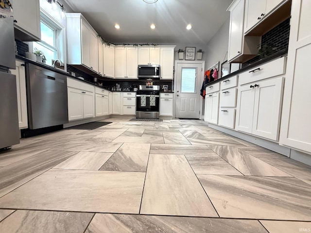 kitchen with white cabinets, decorative backsplash, dark countertops, stainless steel appliances, and recessed lighting