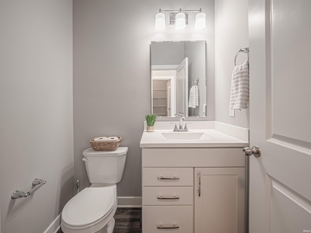 bathroom featuring toilet, baseboards, and vanity