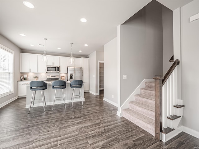 kitchen with stainless steel appliances, dark wood-type flooring, white cabinets, and a center island