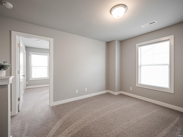 carpeted empty room featuring visible vents and baseboards