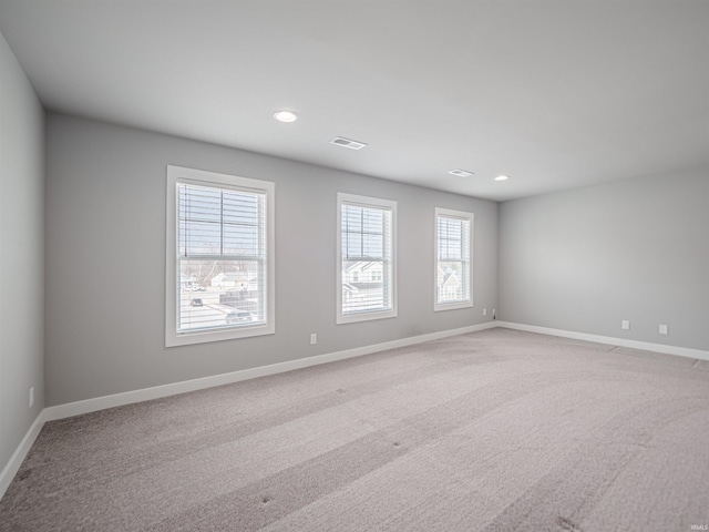 spare room featuring light colored carpet, visible vents, baseboards, and recessed lighting