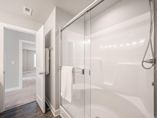 bathroom featuring visible vents, a shower stall, baseboards, and wood finished floors