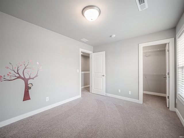 unfurnished bedroom with visible vents, baseboards, carpet, a walk in closet, and a closet