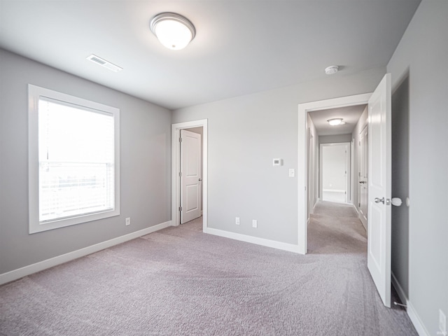 unfurnished bedroom with carpet floors, visible vents, and baseboards