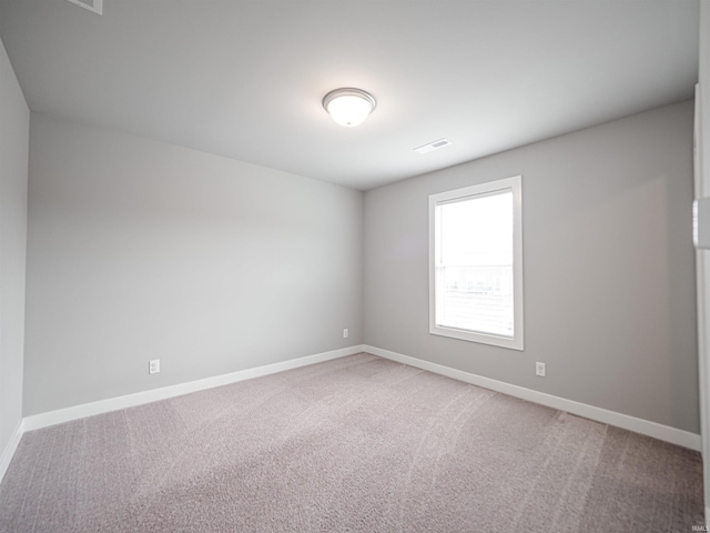 empty room featuring light carpet, visible vents, and baseboards