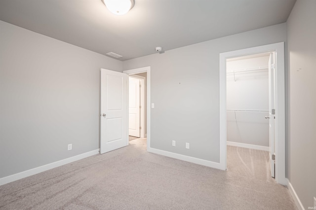 unfurnished bedroom with carpet floors, visible vents, a spacious closet, and baseboards