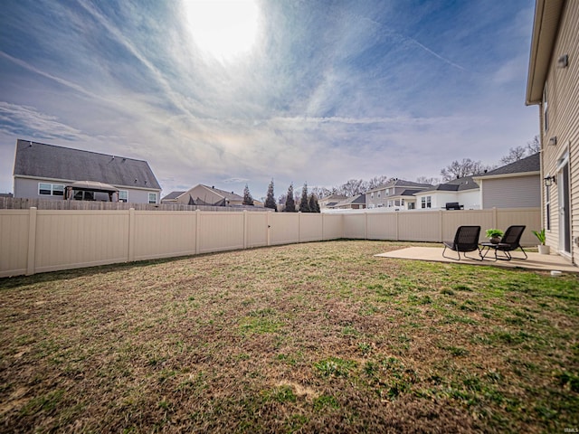 view of yard featuring a fenced backyard, a residential view, and a patio