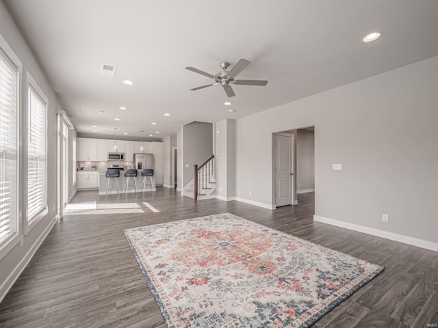 unfurnished living room with stairs, baseboards, dark wood-style flooring, and recessed lighting