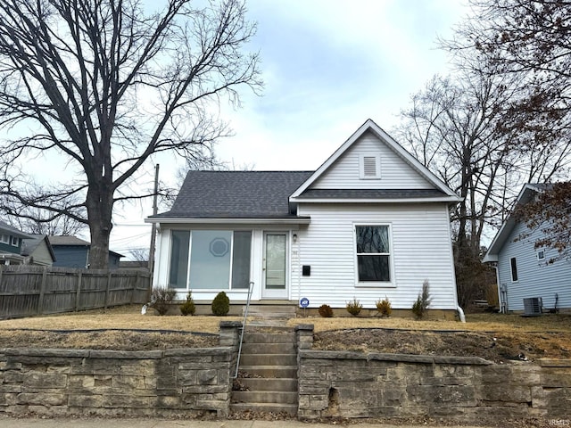 view of front of house with fence, cooling unit, and roof with shingles