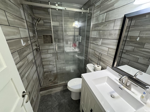 full bath featuring toilet, tile patterned flooring, vanity, a shower stall, and tile walls