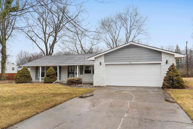 single story home featuring a garage, concrete driveway, brick siding, and a front lawn