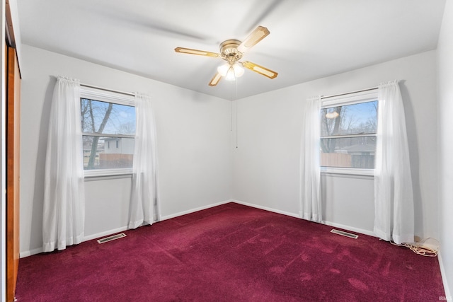 carpeted spare room with baseboards, visible vents, and a ceiling fan