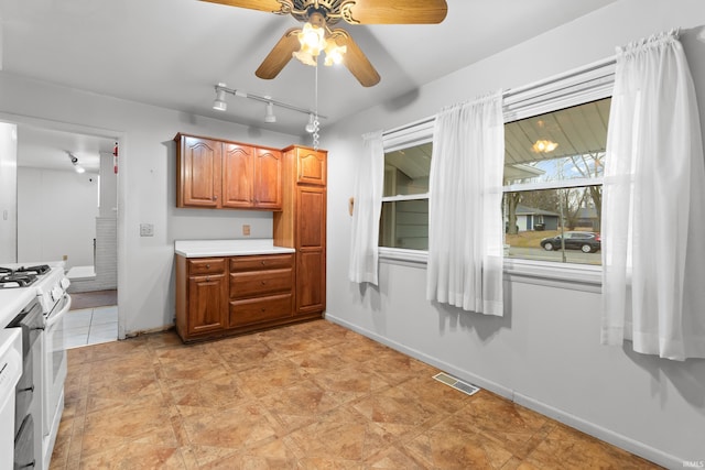 kitchen with brown cabinetry, white gas range, visible vents, and light countertops