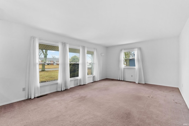 unfurnished room featuring carpet flooring, visible vents, and baseboards