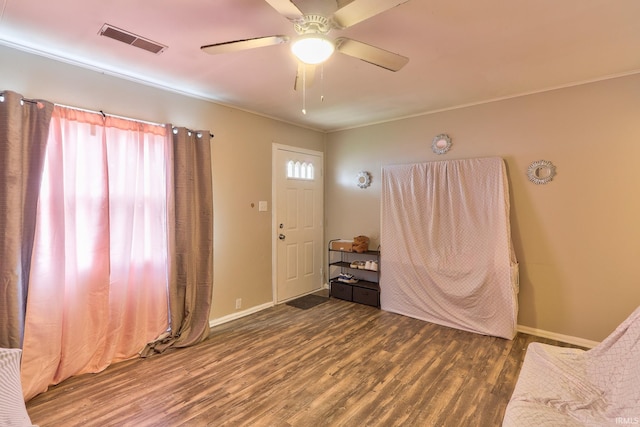 foyer entrance with baseboards, wood finished floors, visible vents, and crown molding