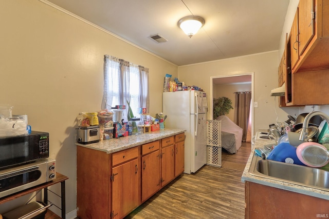 kitchen featuring dark wood-type flooring, visible vents, light countertops, freestanding refrigerator, and brown cabinetry