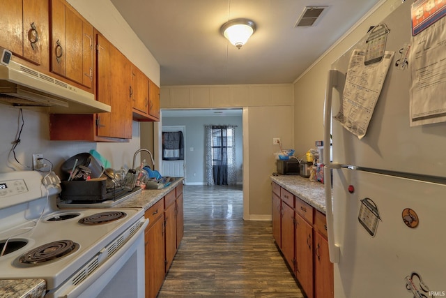 kitchen with white appliances, visible vents, brown cabinetry, dark wood-style floors, and under cabinet range hood