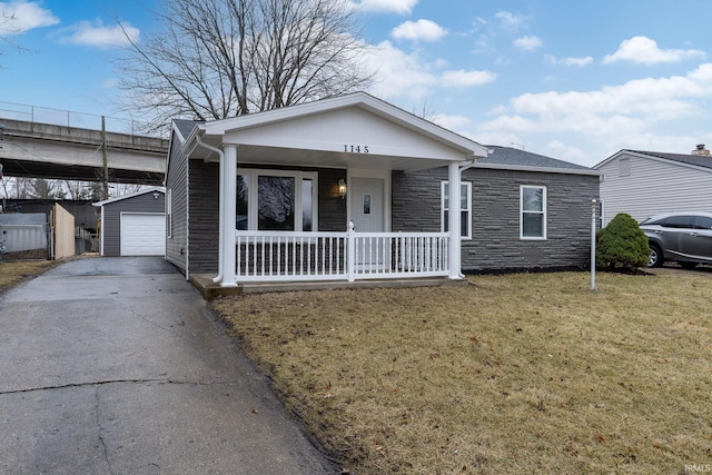 view of front of property with aphalt driveway, covered porch, an outdoor structure, stone siding, and a front lawn