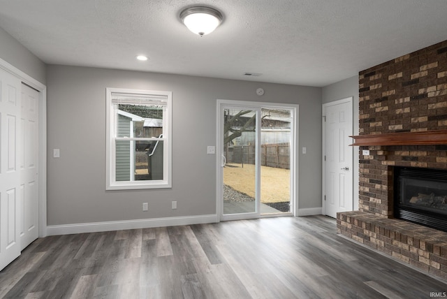 unfurnished living room featuring baseboards, visible vents, a textured ceiling, and wood finished floors