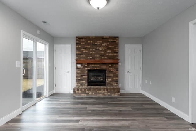 unfurnished living room featuring visible vents, a fireplace, baseboards, and wood finished floors