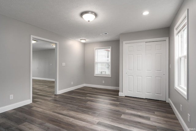 unfurnished bedroom featuring dark wood-type flooring, visible vents, and baseboards