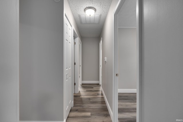 corridor with baseboards, visible vents, and wood finished floors