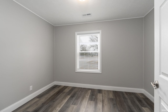 empty room with crown molding, dark wood-type flooring, visible vents, and baseboards