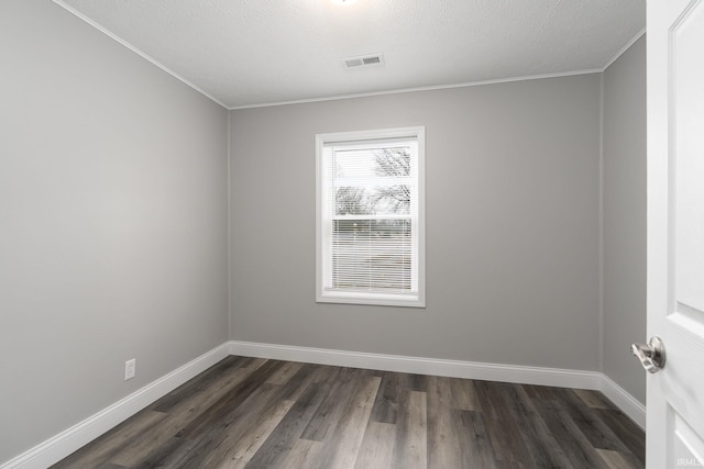 empty room featuring visible vents, dark wood-type flooring, ornamental molding, a textured ceiling, and baseboards