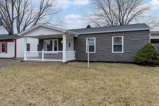 single story home with stone siding, a shingled roof, covered porch, and a front yard